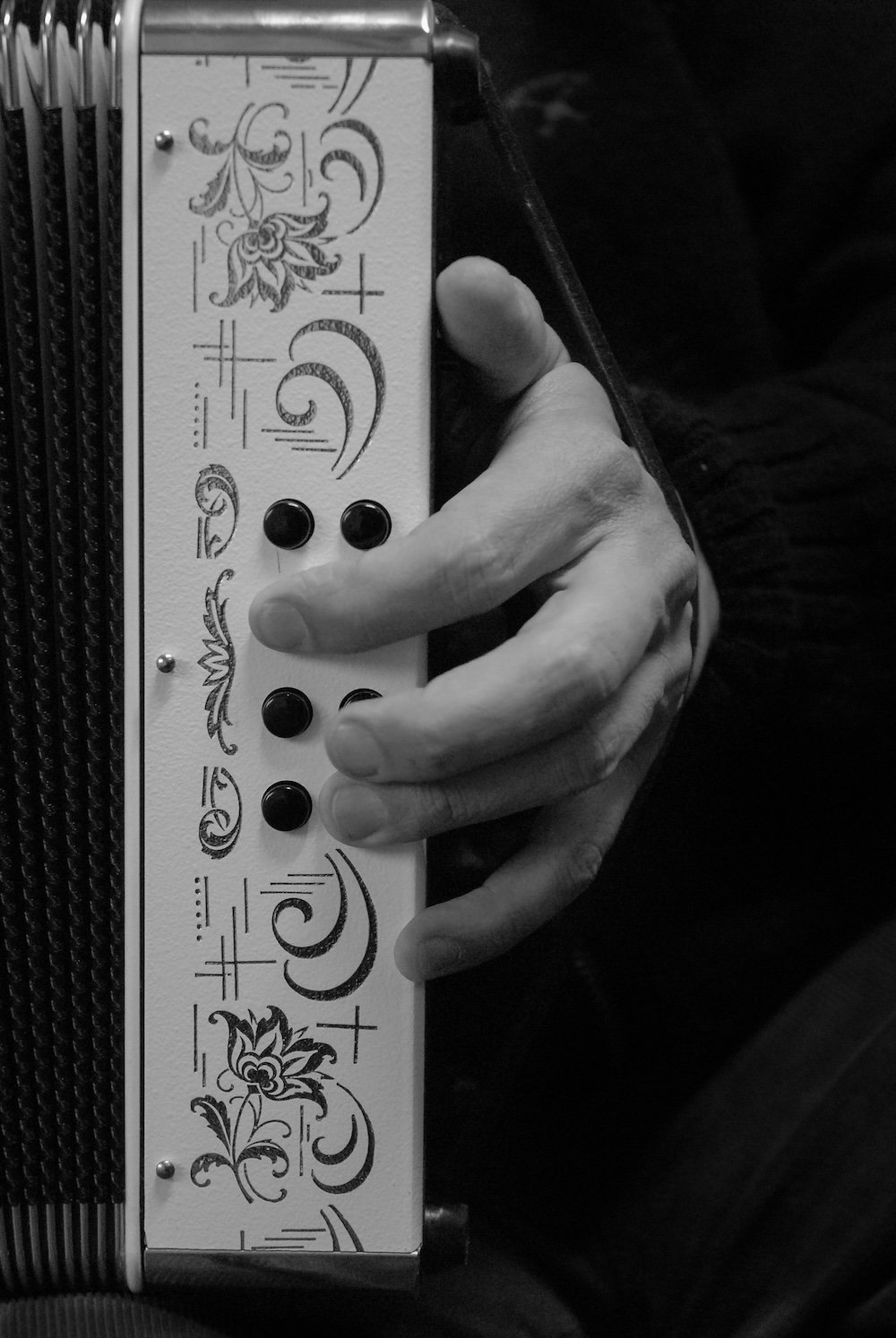 Vertical shot of male hand playing on an old accordion